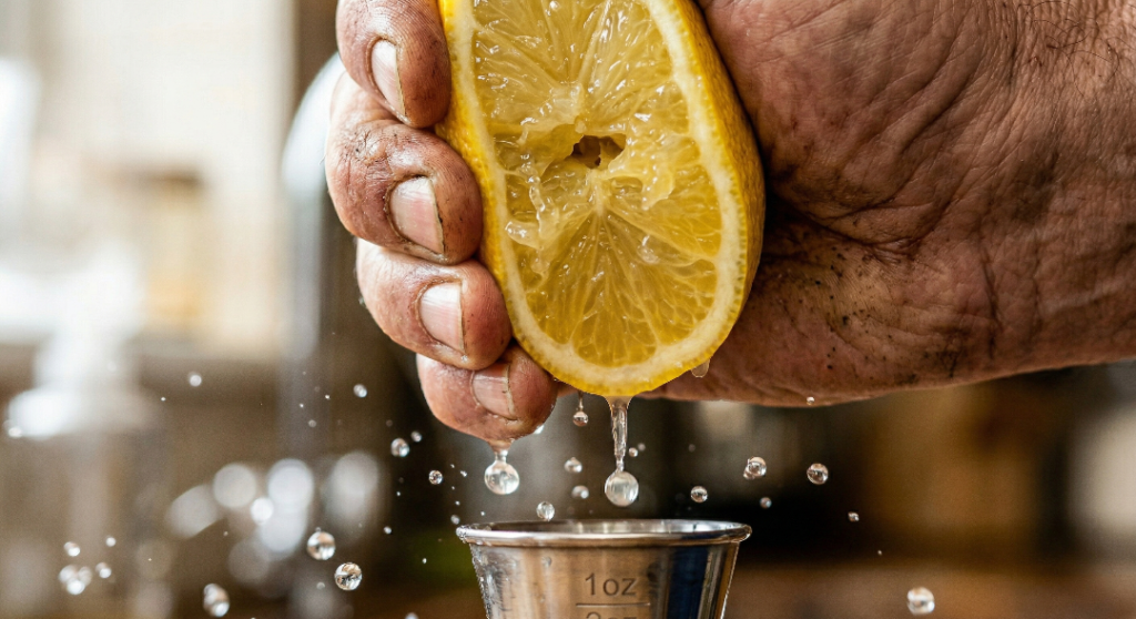Squeezing fresh lemon juice into a jigger for a cocktail recipe.