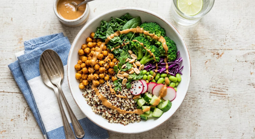 A high-protein vegetarian gym bowl featuring roasted chickpeas, quinoa, and a creamy peanut sauce drizzle.